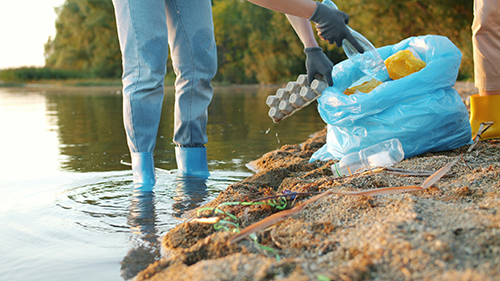photo of people collecting recycling, plastic bottles left in the water and on the beach